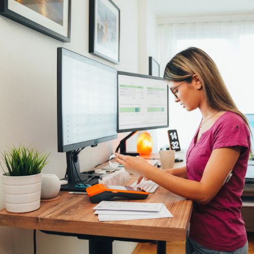 femme devant bureau assis debout ergonomique au travail devant un ordinateur